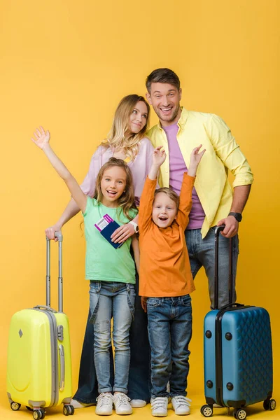 Família alegre de viajantes com bagagem, passaportes e bilhetes em amarelo — Fotografia de Stock
