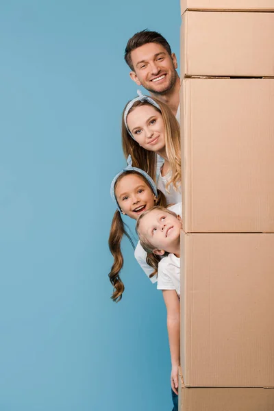 Happy parents and kids with cardboard boxes for relocation on blue — Stock Photo