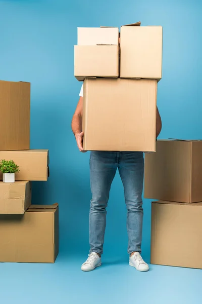 Uomo in possesso di scatole di cartone per il trasferimento su blu — Foto stock