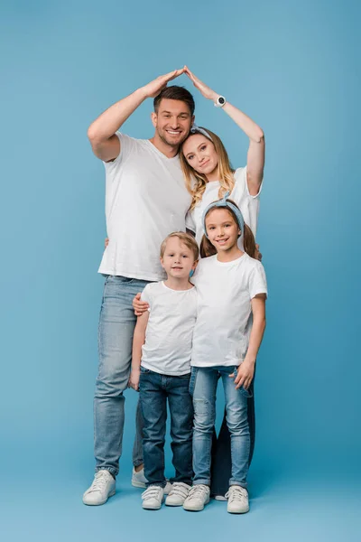 Happy family with kids making roof gesture over heads on blue — Stock Photo