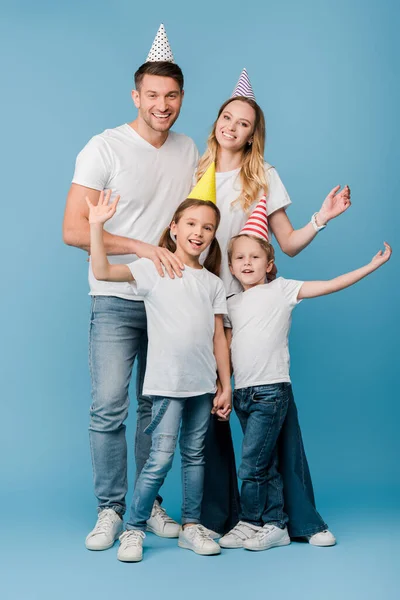 Cheerful family in birthday party caps on blue — Stock Photo