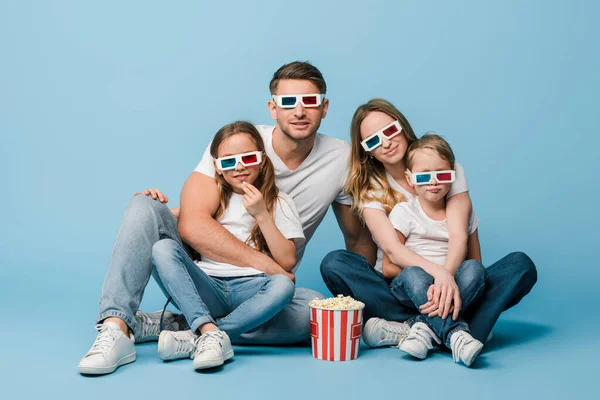 Família feliz assistindo filme em óculos 3d com balde de pipoca em azul — Fotografia de Stock