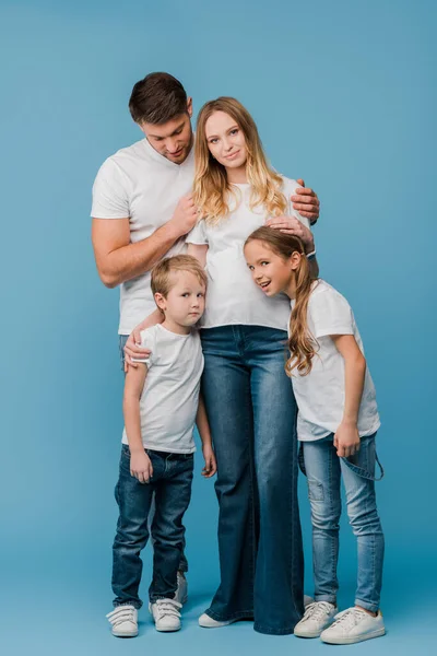 Emotional husband and kids hugging pregnant wife on blue — Stock Photo