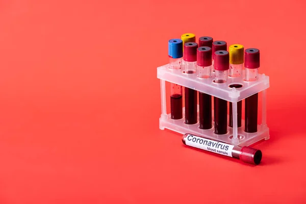 Test tube with blood sample and coronavirus lettering on red — Stock Photo