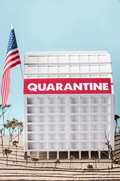 Modello ospedale in cartone con iscrizione di quarantena vicino alla bandiera americana isolata su blu — Foto stock