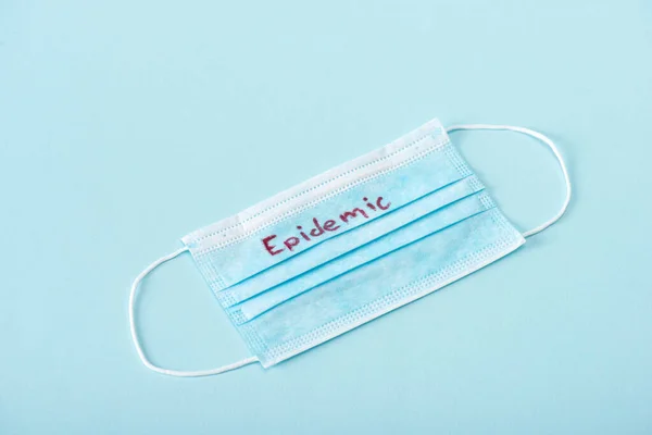 Medical mask with epidemic lettering on blue — Stock Photo