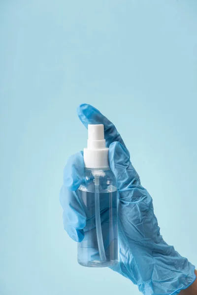 Vue recadrée du médecin en gant de latex tenant bouteille de pulvérisation avec désinfectant pour les mains isolé sur bleu — Photo de stock