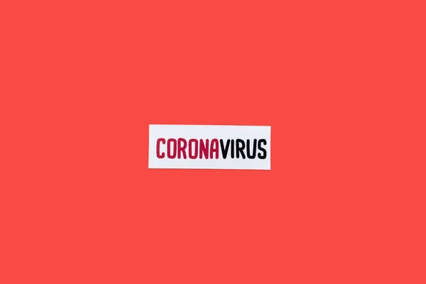 Top view of card with coronavirus lettering isolated on red — Stock Photo