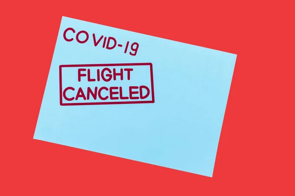 Top view of blue envelope with covid-19 and flight canceled lettering isolated on red — Stock Photo