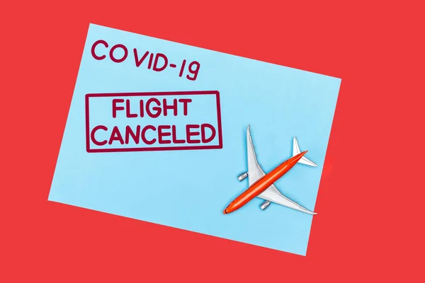 Draufsicht auf blauen Umschlag mit Covid-19 und Flugausfall-Schriftzug in der Nähe von Spielzeugflugzeug isoliert auf rot — Stockfoto