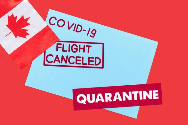 Top view of blue envelope with covid-19, flight canceled and quarantine lettering near flag of canada isolated on red — Stock Photo