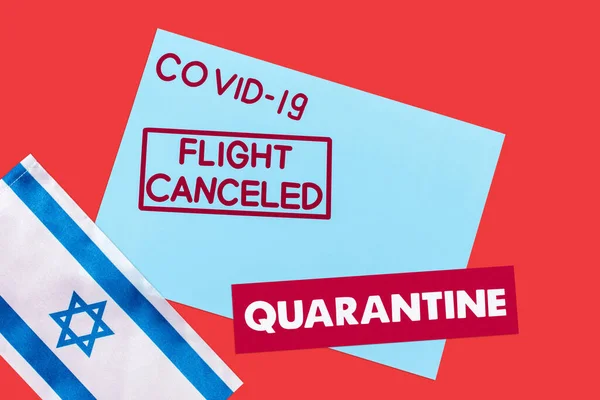 Top view of blue envelope with covid-19, flight canceled and quarantine lettering near flag of israel isolated on red — Stock Photo