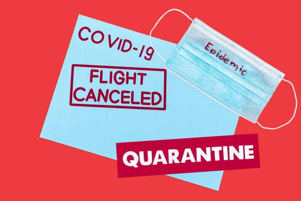 Draufsicht auf den blauen Umschlag mit Covid-19, Flugausfall und Quarantäne-Schriftzug in der Nähe der medizinischen Maske auf Rot isoliert — Stockfoto