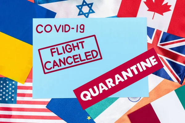 Top view of blue envelope with covid-19, flight canceled and quarantine lettering on different flags — Stock Photo