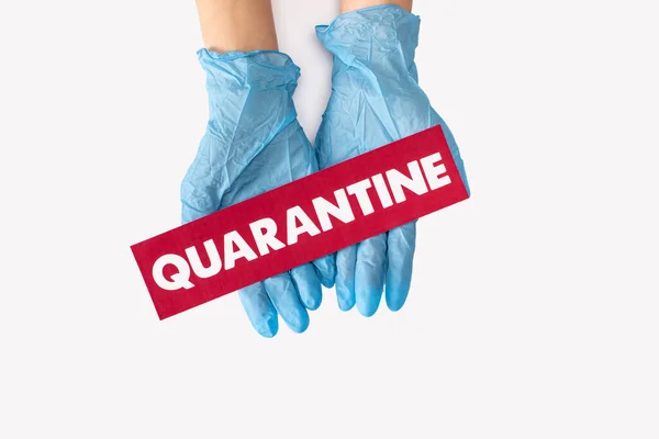 Top view of doctor in latex gloves holding card with quarantine lettering isolated on white — Stock Photo
