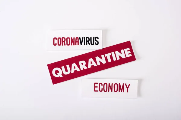 Vista superior de tarjetas con letras de cuarentena, coronavirus y economía en blanco - foto de stock