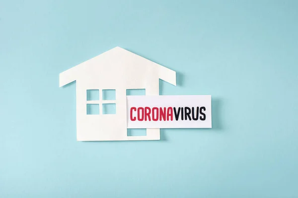 Верхний вид бумажного дома рядом с коронавирусной надписью на голубом — стоковое фото