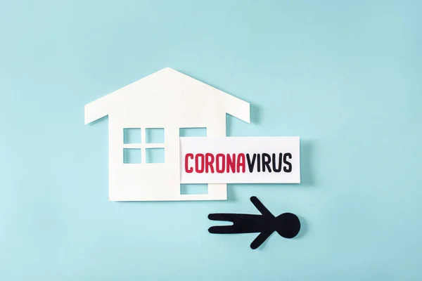 Ansicht von Papierhaus und menschennahem Coronavirus Schriftzug auf blau — Stockfoto