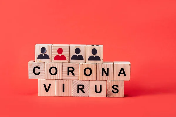 Wooden cubes with coronavirus lettering and people icons on red — Stock Photo