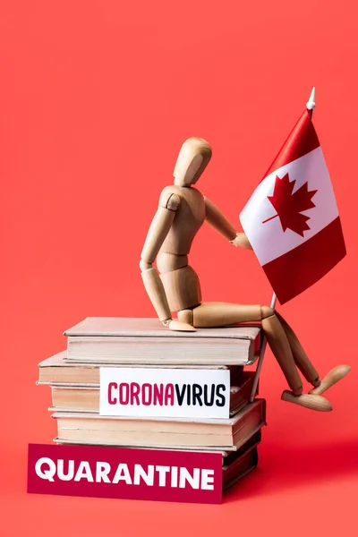 Wooden doll with flag on canada books near cards with quarantine and coronavirus lettering on red — Stock Photo