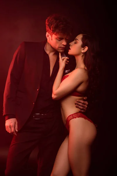 Couple intime étreignant et allant embrasser sur noir avec la lumière rouge — Photo de stock