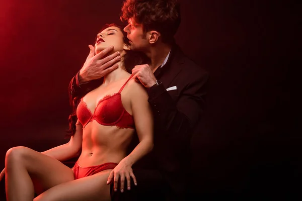 Інтимна пара обіймається на чорному з червоним світлом — стокове фото