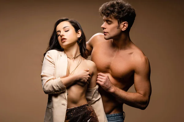 Handsome man hugging sensual half naked woman in beige jacket on beige — Stock Photo