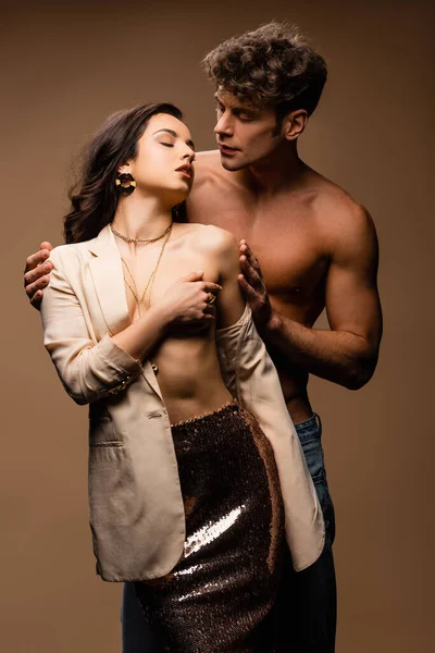 Handsome shirtless man hugging passionate half naked woman in beige jacket on beige — Stock Photo