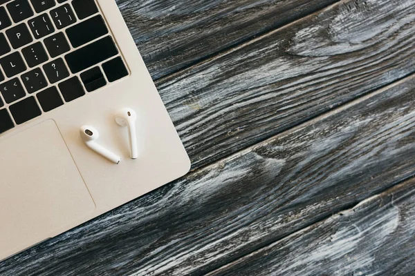 Vista dall'alto di laptop e auricolari su una superficie di legno scuro — Foto stock