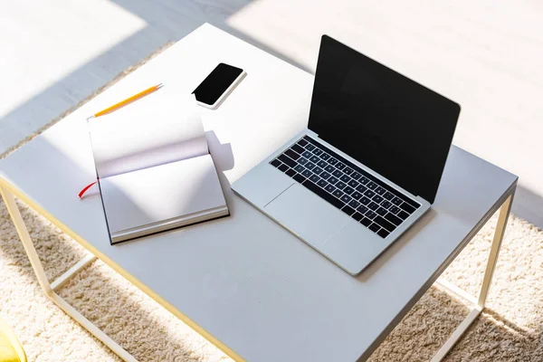 Empty workplace with laptop, smartphone, notepad and pencil in sunlight — Stock Photo
