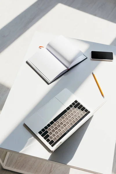 Empty workplace with laptop, smartphone, notepad and pencil — Stock Photo