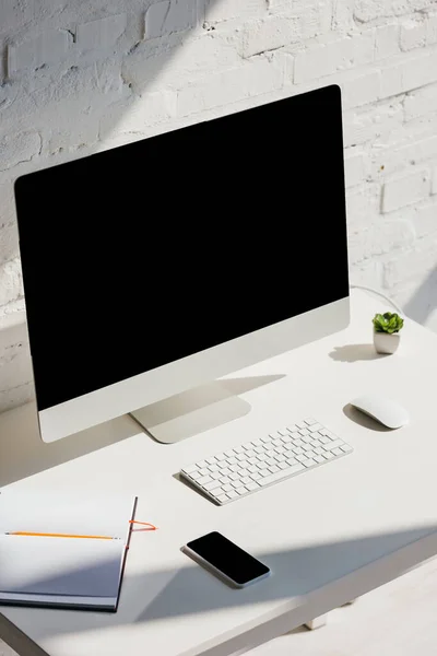 Home office com computador e smartphone com telas em branco — Fotografia de Stock