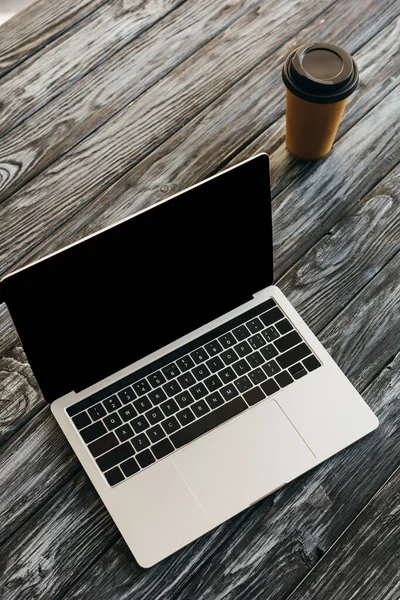 Café para llevar y portátil con pantalla en blanco en la superficie de madera oscura - foto de stock