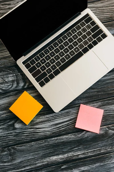 Top view of laptop with blank screen and sticky notes on dark wooden surface — Stock Photo