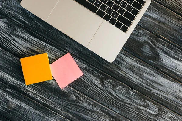 Top view of laptop and sticky notes on dark wooden surface — Stock Photo