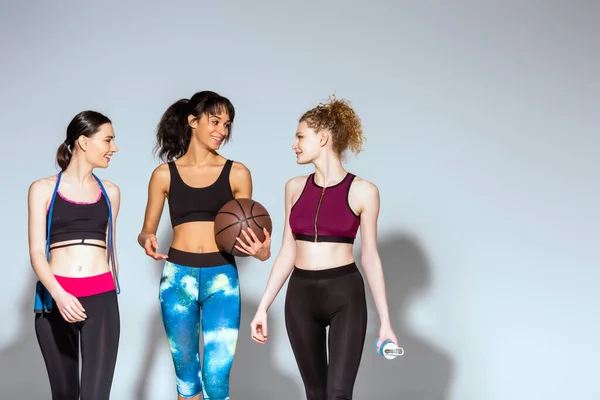 Allegra ragazza afroamericana in possesso di basket e camminare con le donne sportive su bianco — Foto stock