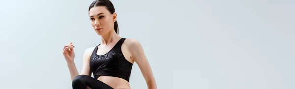 Plano panorámico de mujer atractiva en ropa deportiva negro ejercicio aislado en blanco - foto de stock