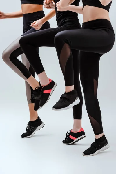 Cropped view of multicultural women in sportswear exercising on white — Stock Photo