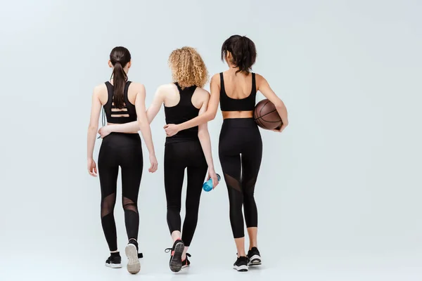 Rückansicht multikultureller Mädchen, die mit Sportgeräten auf weiß laufen — Stockfoto