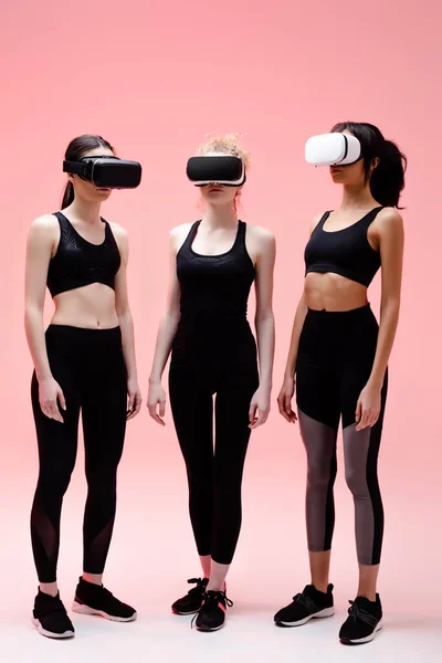 Multikulti-Frauen in Sportbekleidung und Virtual-Reality-Headsets auf rosa — Stockfoto