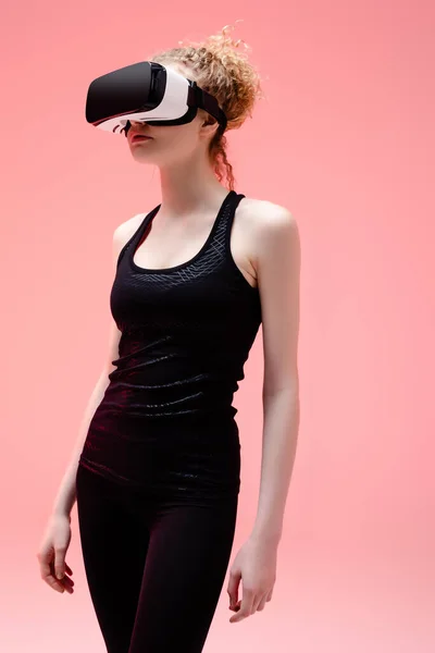 Спортивная женщина в спортивной одежде и гарнитуре виртуальной реальности на розовом — стоковое фото