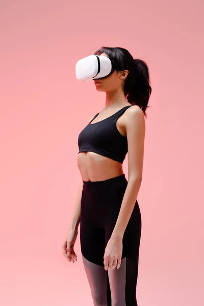 Молодая африканская американка в спортивной одежде и гарнитуре виртуальной реальности на розовом — стоковое фото
