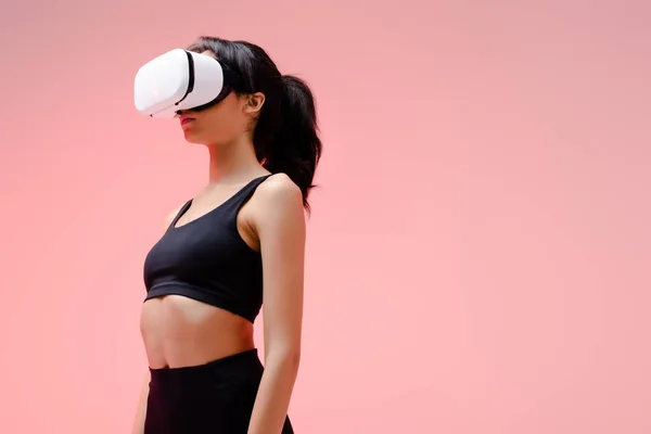 Donna afroamericana in abbigliamento sportivo e auricolare realtà virtuale su rosa — Foto stock