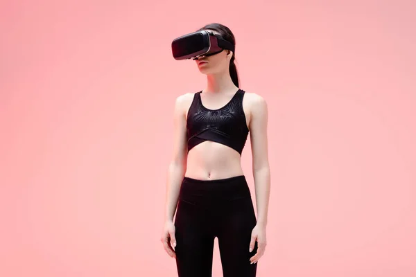 Young sportswoman in virtual reality headset standing on pink — Stock Photo