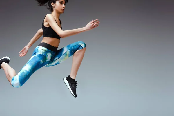 African american sportswoman in sportswear jumping on grey — Stock Photo