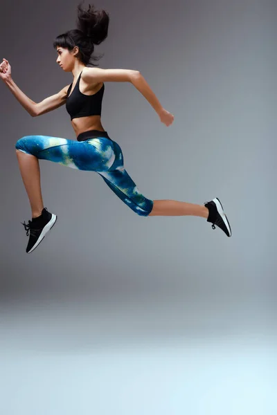 Side view of african american girl in sportswear jumping on grey — Stock Photo