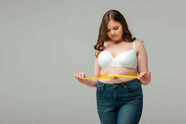 Plus size girl in jeans taillenmaß isoliert auf grau — Stockfoto