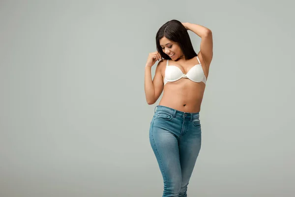 Femme afro-américaine en surpoids et heureux en jeans et soutien-gorge debout isolé sur gris — Photo de stock