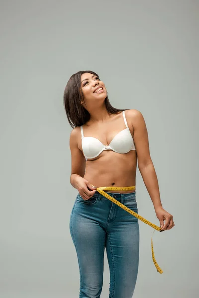 Felice e sovrappeso ragazza afroamericana in jeans e reggiseno di misura vita isolato su grigio — Foto stock