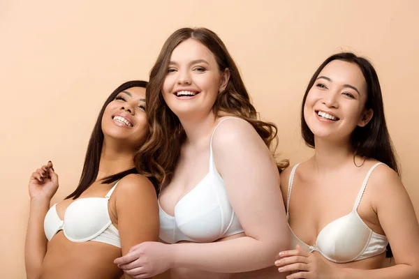 Alegre más tamaño multicultural de las mujeres en sujetadores aislados en beige - foto de stock